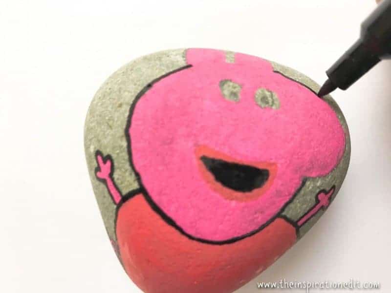 using a black posca pen to add detail while rock painting using a black posca pen to add detail while rock painting