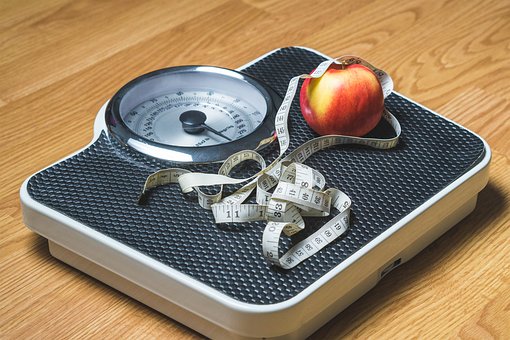 Scale with tape measure and apple on top of it.