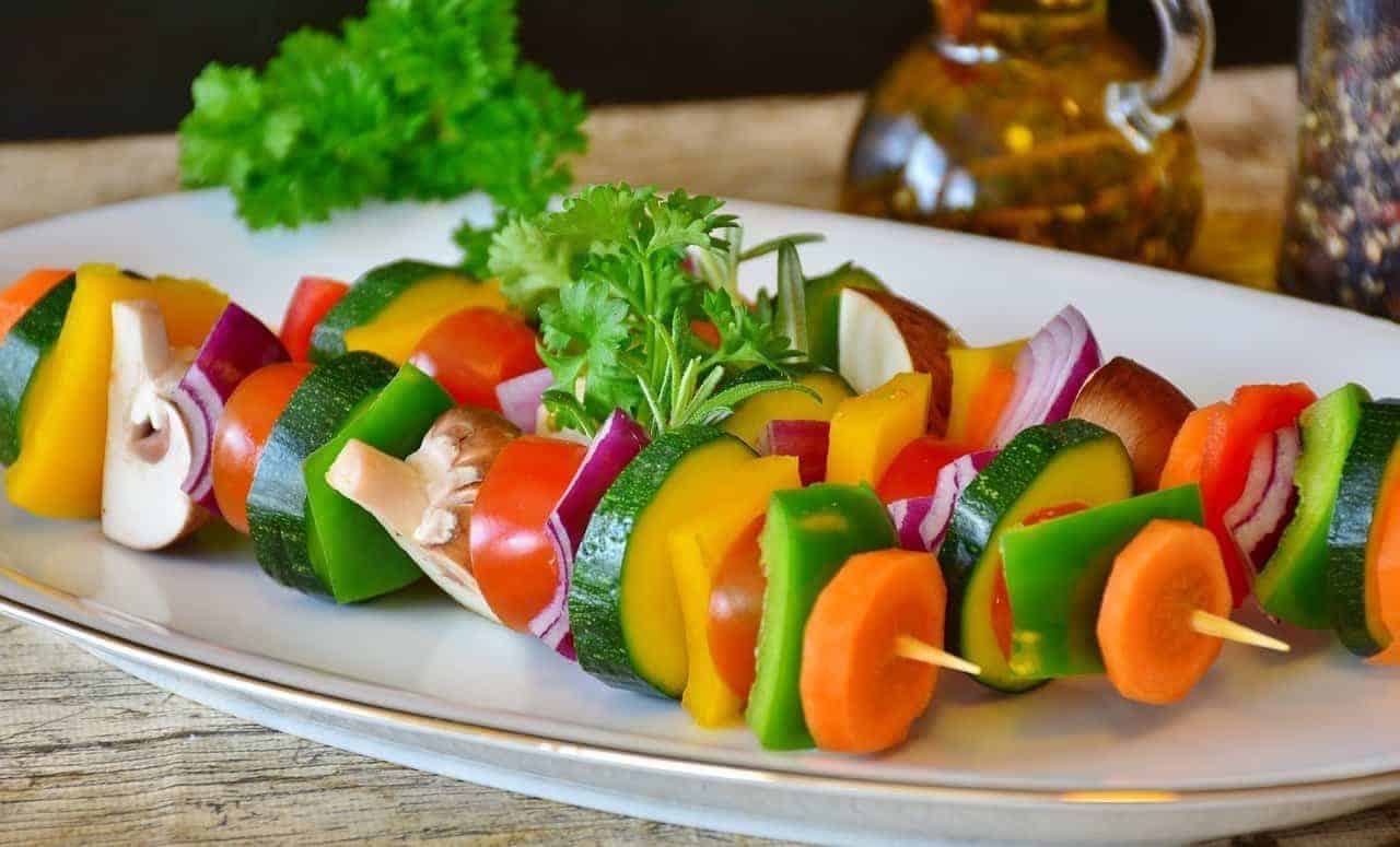 Bright-colored vegetables on skewers on a plate.