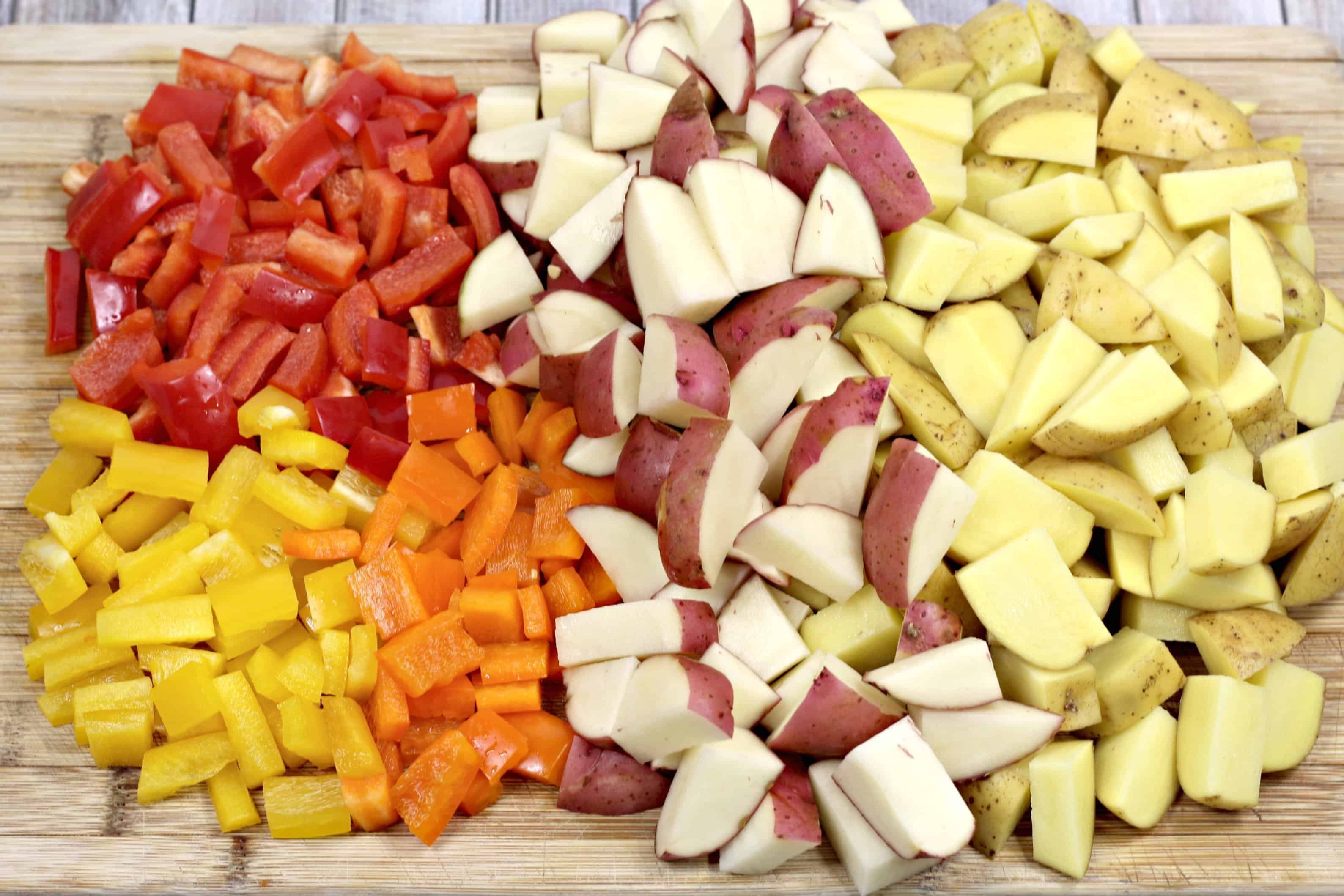 Chopped potatoes and peppers on a cutting board.