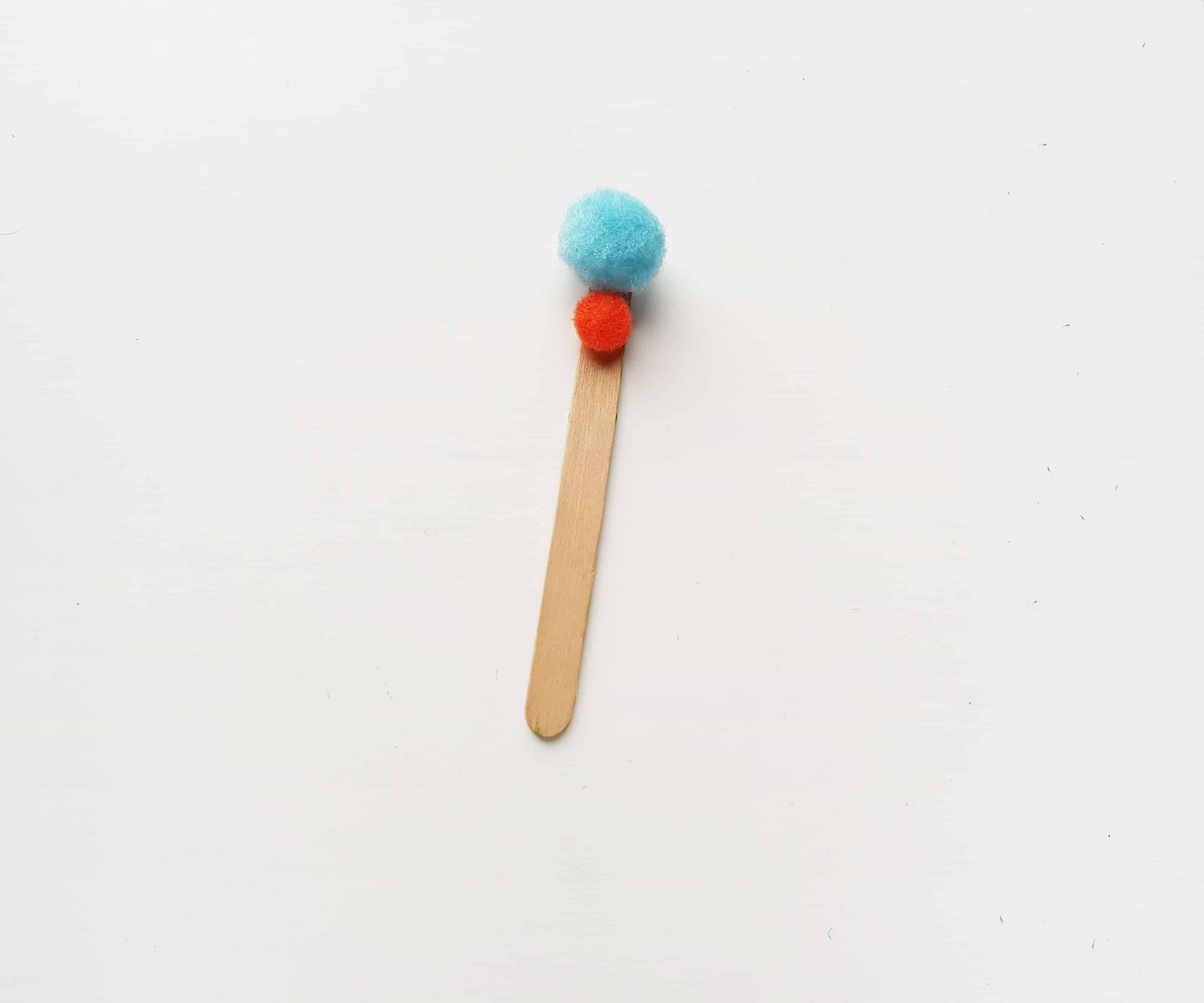 Gluing a Pom Pom onto the Popsicle Stick.