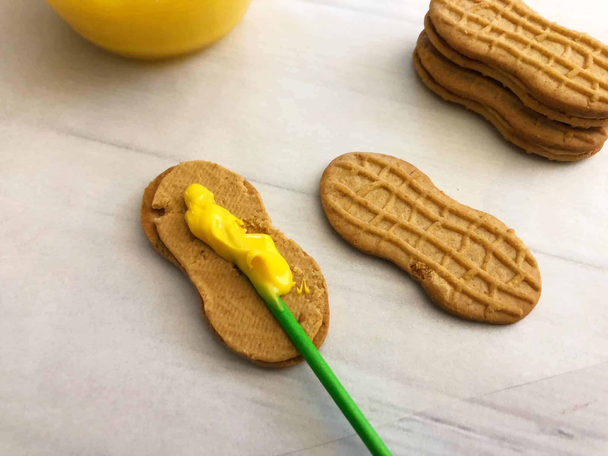Sticking lollipop stick with melted chocolate between Nutter Butters.