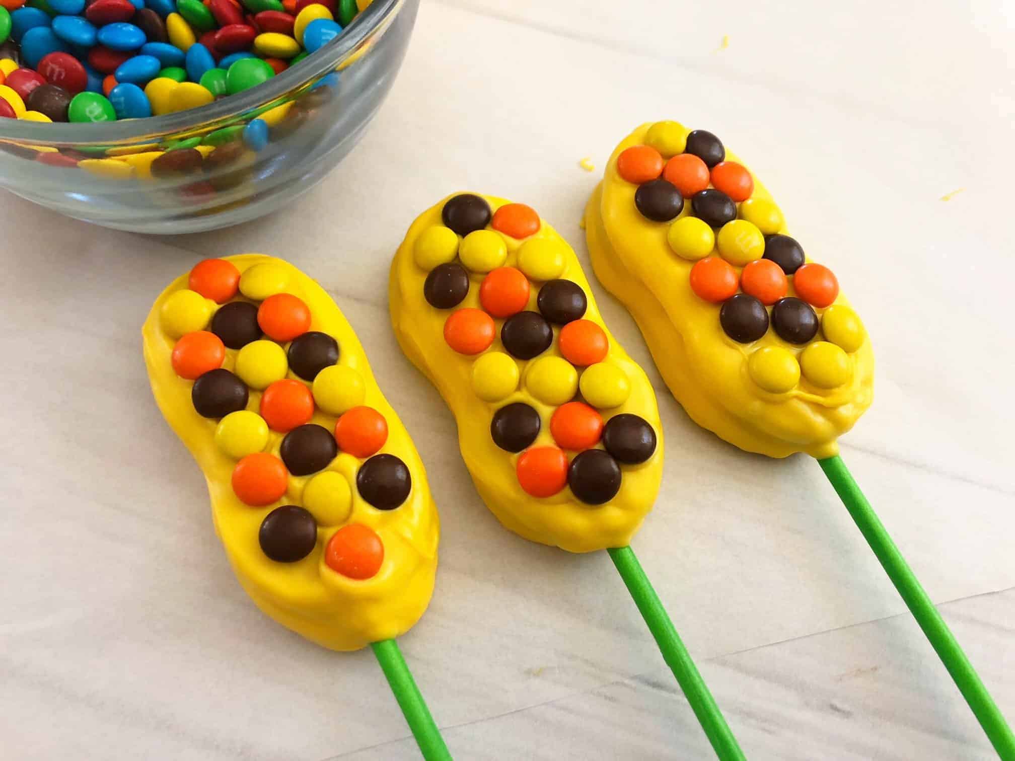 Yellow chocolate covered Nutter Butters topped with M&Ms.