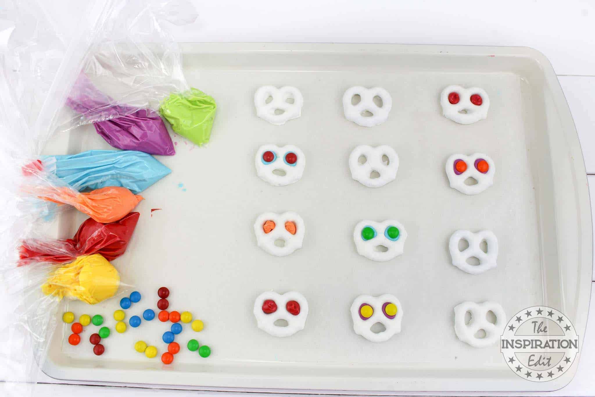 Different colored melted chocolate in each in separate piping bag and pretzels.