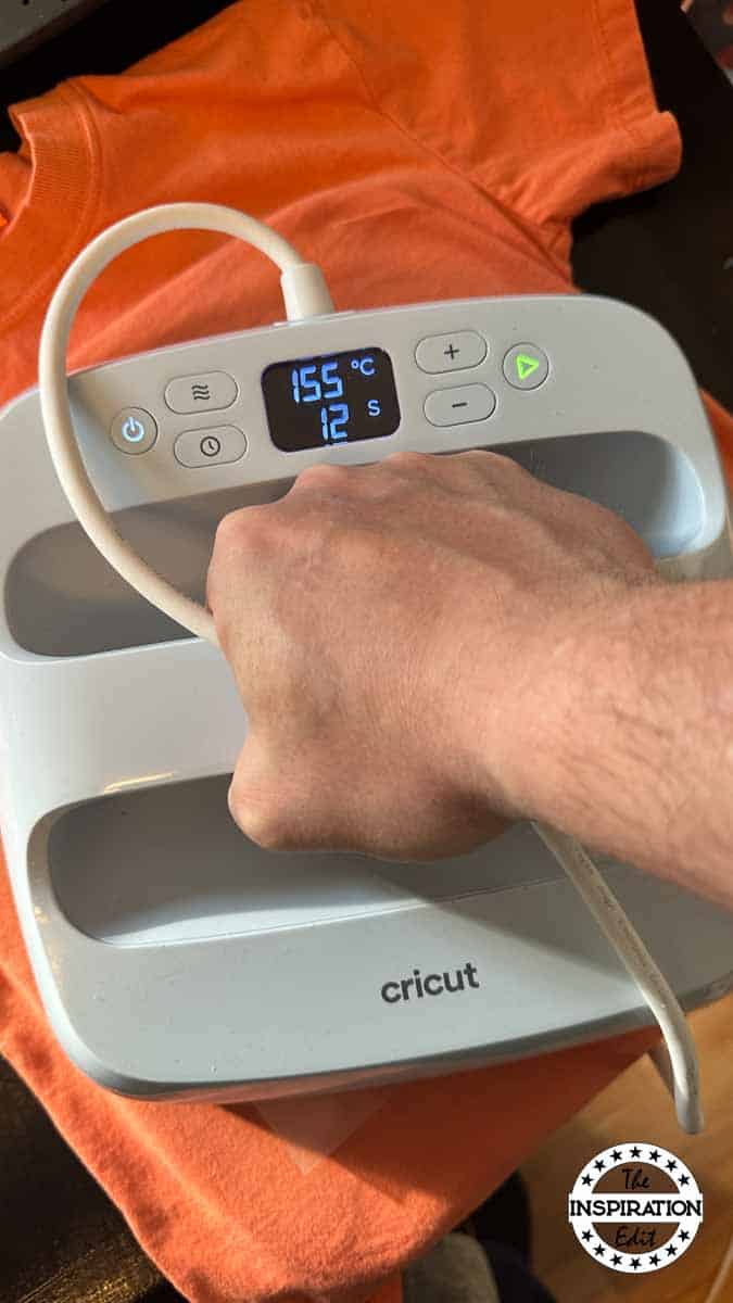 using a cricut press to iron onto an orange t-shirt.