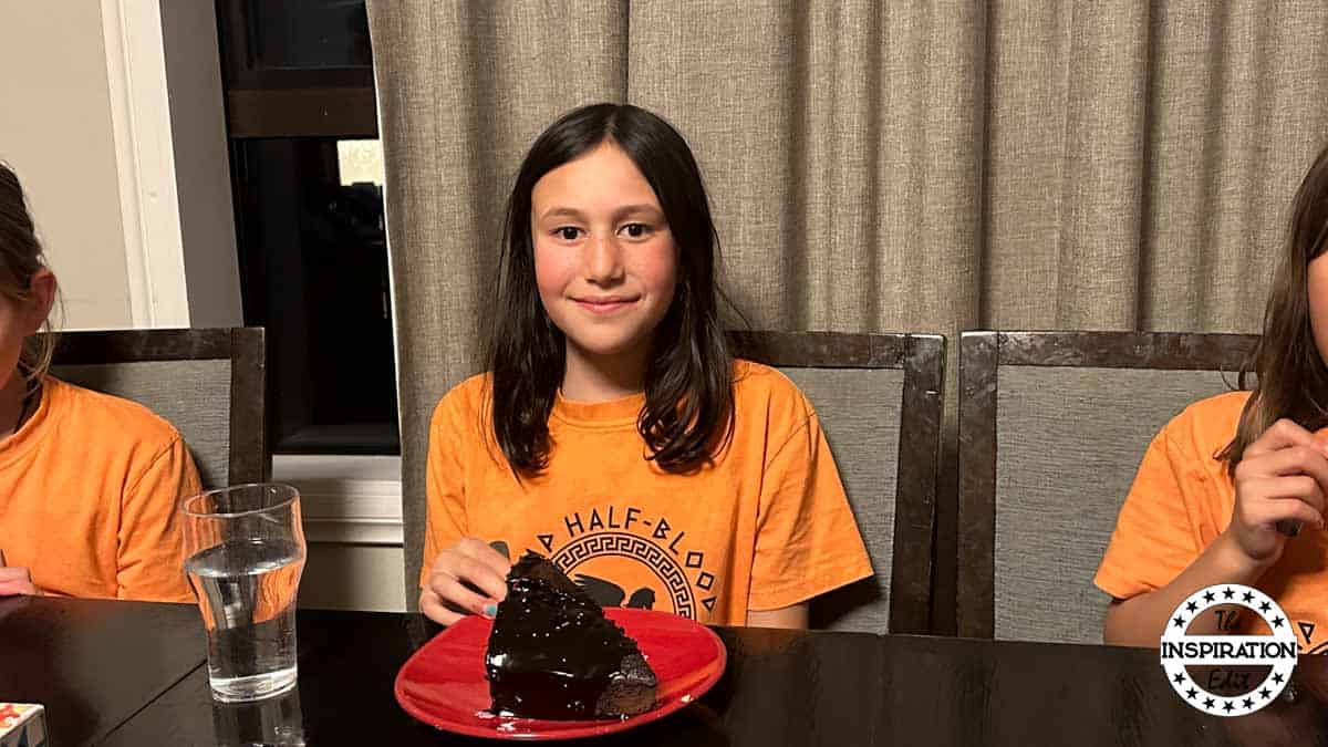 child at a percy jackson party eating cake.