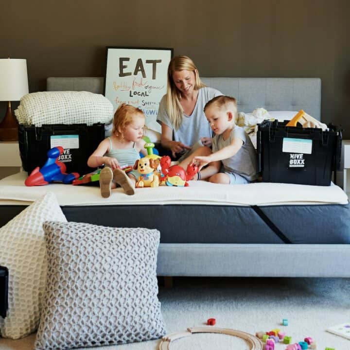 Make moving fun for the whole family | Mom and kids sitting on a bed, getting stuff ready to move house.