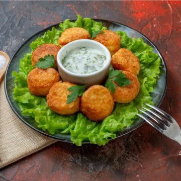 Air-fried-chicken-nuggets-served-with-a-bowl-of-sauce-and-lettuce-on-a-plate.